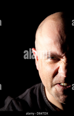 Désemparé homme chauve avec la moitié en face de l'ombre profonde d'un fond noir. Banque D'Images