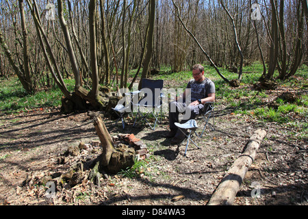 L'homme dans son début des années 30, la consommation de bière et à la fed up en camping dans les bois. Banque D'Images