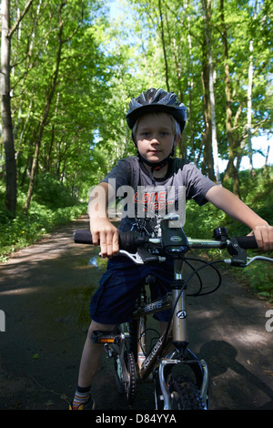 Garçon blond enfant 6 - 7 ans équitation vélo avec casque de vélo en cours de l'été Banque D'Images