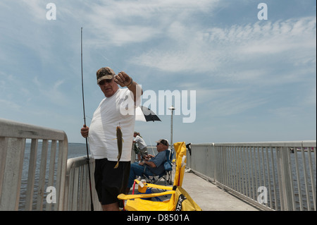 L'homme pêche sur le quai public à Cedar Key en Floride sur la côte du golfe du Mexique, exhibant sa fontaine Banque D'Images