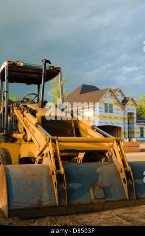 Pelleteuse en face de nouvelles maisons en construction résidentielle Banque D'Images