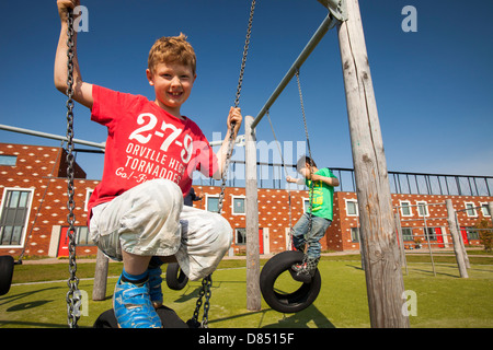 Les enfants jouent sur des balançoires en face de maisons à Almere avec panneaux solaires photovoltaïques sur le toit. Banque D'Images