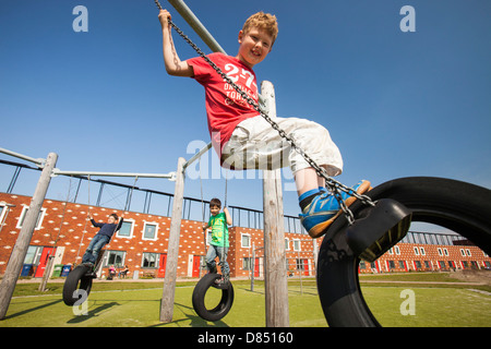 Les enfants jouent sur des balançoires en face de maisons à Almere avec panneaux solaires photovoltaïques sur le toit. Banque D'Images