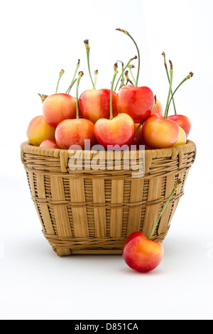 Rainier cherries assis dans un panier isolé sur un fond blanc. Banque D'Images