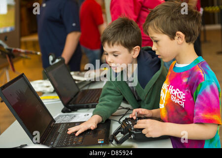 Garden City, New York, USA. 19 mai 2013. Deux jeunes garçons utiliser type de télécommande pour piloter des avions en vol simulé sur des ordinateurs portables au congrès annuel de l'Flying Model Show parrainé par Academy of Model Aeronautics (AMA) et le modèle des clubs de l'avion de Nassau, Suffolk & Queens, dans le hall de la Berceau de l'Aviation Museum. Credit : Ann E Parry / Alamy Live News Banque D'Images