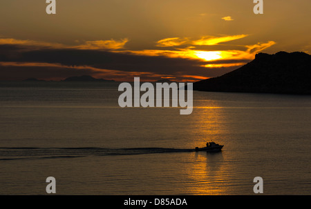 Golden orange coucher de soleil avec des reflets et bateau de pêche, Mer Égée, Kalymnos, Grèce Banque D'Images