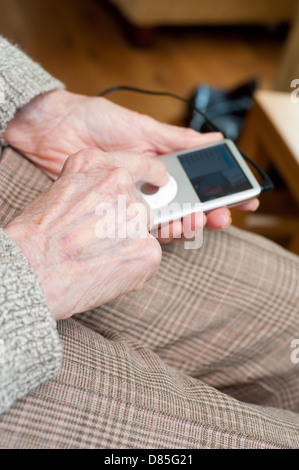 Une femme âgée à l'aide d'un iPod Banque D'Images