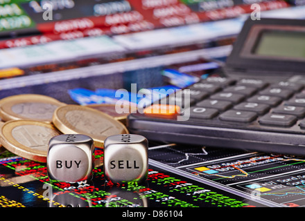 Dés cubes avec mots vendre acheter pour le commerçant, les pièces en euros et Calculatrice. Tableau financier comme arrière-plan. Selective focus Banque D'Images