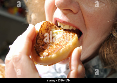 Woman eating a hot buttered pour le petit-déjeuner ou un thé crumpet Banque D'Images