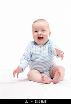 Beau rire happy baby boy sitting on bed blanc Banque D'Images