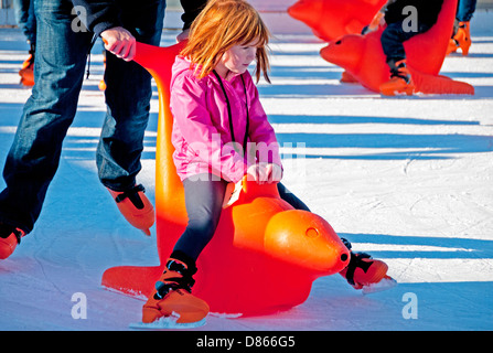 Jeune fille le patin à glace -- être poussé dans un leurre -- à une patinoire portable à Alameda, Californie Banque D'Images