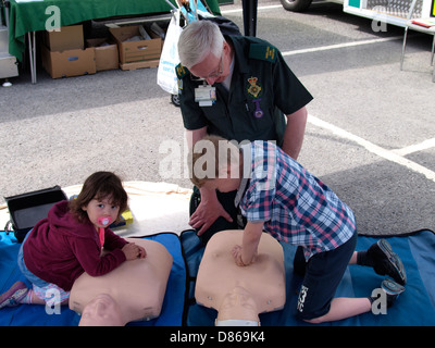 Richard Oaten de l'Ambulance avec quelques jeunes enfants faire la RCR sur une pratique mannequin, Barnstaple, Devon, UK 2013 Banque D'Images