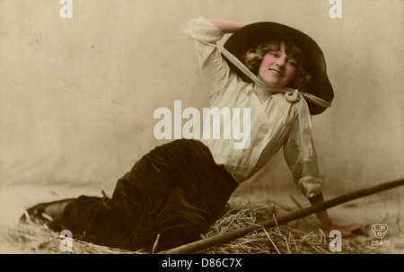 Jeune femme dans un grand chapeau assis sur la paille Banque D'Images