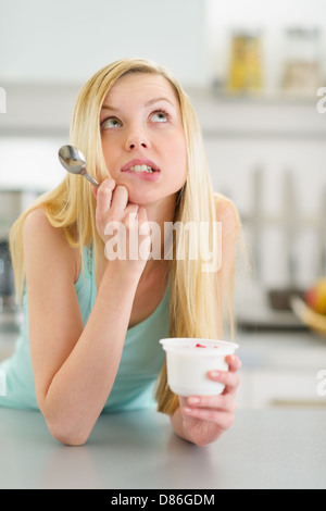 Portrait de jeune fille adolescente réfléchie avec du yaourt dans la cuisine Banque D'Images