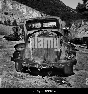 Rusty voiture abandonnée et les machines industrielles dans une carrière. Noir et blanc. Banque D'Images