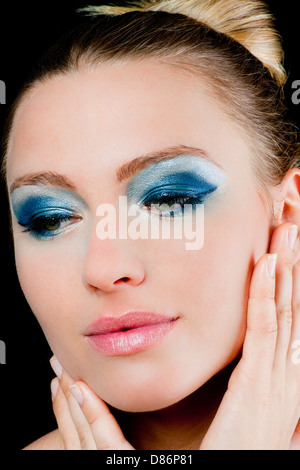 Belle jeune femme aux yeux verts portant un miroir bleu et rouge à lèvres Rose tenant la main à son visage Banque D'Images