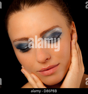 Belle jeune femme portant un miroir bleu et rouge à lèvres Rose tenant la main à son visage Banque D'Images