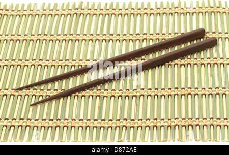 Baguettes en bois sombre sur le tapis de bambou Banque D'Images