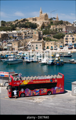 Un tour bus attend les passagers du traversier sur l'île maltaise de Gozo. Le port de Mgarr est dans l'arrière-plan Banque D'Images