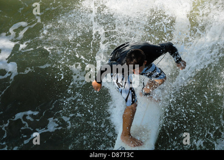 Surfer la vague d'équitation à Jacksonville Beach, Floride et s'apprêtait à tourner les pilots sous le Jacksonville Beach Pier. USA. Banque D'Images