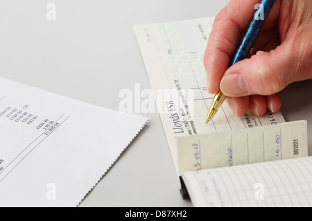 Femme âgée femme écrivant un pensionné Lloyds TSB chèque pour payer une grande carte de crédit. En Angleterre, Royaume-Uni, Angleterre Banque D'Images