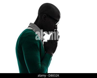 Un homme noir africain pense pensive priant en silhouette silhouette studio sur fond blanc Banque D'Images