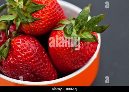 Libre d'un grand bol de fraises fraîches en orange sur un fond sombre Banque D'Images