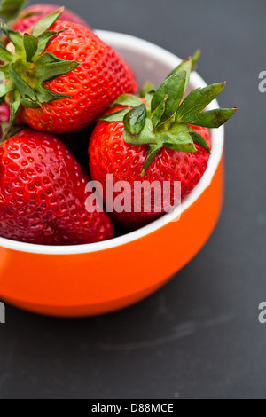 Libre d'un grand bol de fraises fraîches en orange sur un fond sombre Banque D'Images