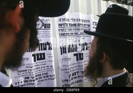 Les Juifs ultra orthodoxes qui lisent Pashkvilim, qui sont grand public ou des affiches situées sur un mur public et servent d'annonces communautaires dans le quartier de Mea Shearim, une enclave ultra-orthodoxe à Jérusalem-Ouest Israël Banque D'Images