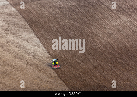 Un tracteur ratisser le champ labouré en préparation pour l'ensemencement des années de récolte. Banque D'Images