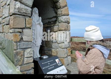 Jeune fille irlandaise priaient à sanctuaire catholique de la Vierge Marie sur l'île d'Aranmore à Donegal. Banque D'Images