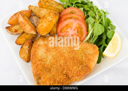 Wiener Schnitzel - steak de veau panés et frits dans le beurre servi avec salade, les quartiers de pommes de terre et une tranche de citron. Banque D'Images