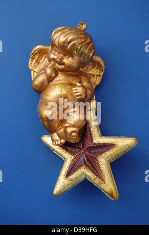 Petit Ange assis sur golden star de noël bauble. Décoration saisonnière. Banque D'Images