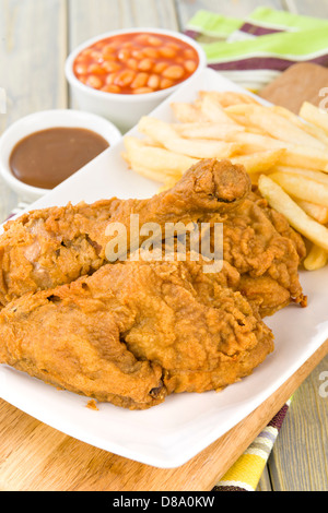 Poulet frit et frites - morceaux de poulet sur l'os enrobés de farine épicée et frits. Frites, haricots blancs et jus de viande et d'autre. Banque D'Images