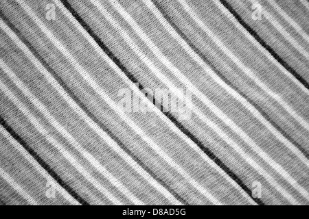 Gros plan d'un tissu tricoté à rayures diagonales, présentant un mélange de gris, noir et blanc. Cette texture ajoute de la profondeur et de l'intérêt visuel aux textiles utilisés dans la mode ou la décoration intérieure. Banque D'Images