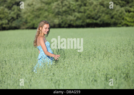 Beautiful teenager fille qui marche en toute sécurité avec une assurance voyage une prairie d'avoine verte de toucher les herbes Banque D'Images