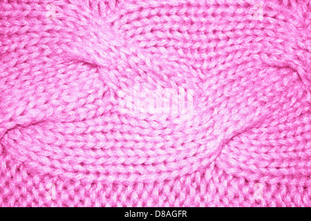 Gros plan d'un tissu tricoté rose, affichant le motif complexe et la texture. Le tricot câblé est une technique populaire pour créer des tissus épais et texturés utilisés dans les vêtements. Banque D'Images