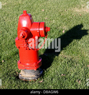 Une bouche d'incendie rouge vif se tient bien en vue sur un coin de rue, prête pour une utilisation d'urgence. La bouche d'incendie robuste et bien entretenue est un élément essentiel de l'infrastructure urbaine pour la sécurité incendie. Banque D'Images