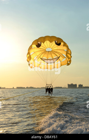 Trois personnes sur une motomarine dans l'océan lors d'un coucher du soleil Banque D'Images