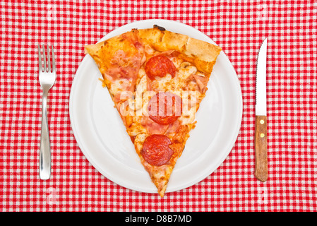 Pepperoni pizza slice on white plate servi sur table. Banque D'Images