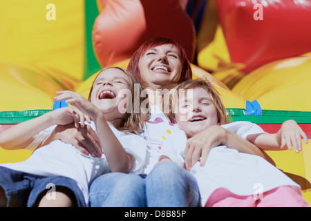 Maman et ses filles rire portant sur un château gonflable dans une journée d'été lumineux à l'extérieur. Belle journée ! Banque D'Images