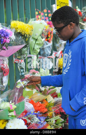 Woolwich, Londres, Royaume-Uni. 23 mai 2013. Un jeune garçon se penche sur les cartes et de fleurs sur les grilles près du lieu du meurtre. Les fleurs sont laissés par les bienfaiteurs le long des rampes près de l'endroit où le batteur Lee Rigby du 2e Bataillon du Régiment royal de fusiliers a été tué hier à l'extérieur des casernes de Woolwich. Crédit : Matthieu Chattle/Alamy Live News Banque D'Images
