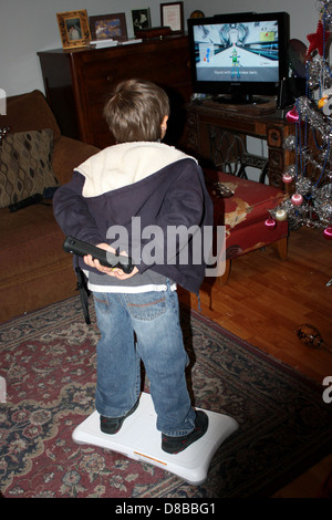 Un enfant s'engageant avec le système de jeu Wii Fit, en équilibre sur la Wii Balance Board pour une expérience de fitness amusante et interactive. Le jeu encourage l'activité physique par le biais d'activités virtuelles. Banque D'Images