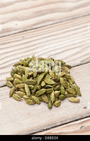 Un petit tas de gousses de cardamome verte sur une surface en bois poncé. Banque D'Images