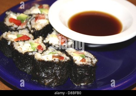 Des rouleaux de sushi fraîchement préparés sont disposés sur une assiette, accompagnés d'une sauce trempante. Les rouleaux de sushi contiennent une variété d'ingrédients, y compris du poisson, des légumes et du riz, reflétant la cuisine japonaise. Banque D'Images