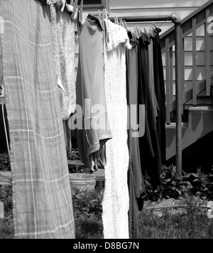 Une photo en noir et blanc de linge accroché à une corde à linge. L'image capture la simplicité de la vie quotidienne avec les vêtements se balançant doucement dans la brise. Banque D'Images