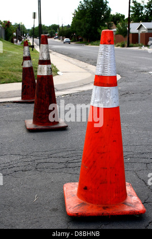 Des cônes orange sont placés à une intersection pour bloquer la circulation. Ces cônes sont couramment utilisés pour éloigner les véhicules des zones de construction, des accidents ou d'autres dangers, assurant ainsi la sécurité sur les routes. Banque D'Images