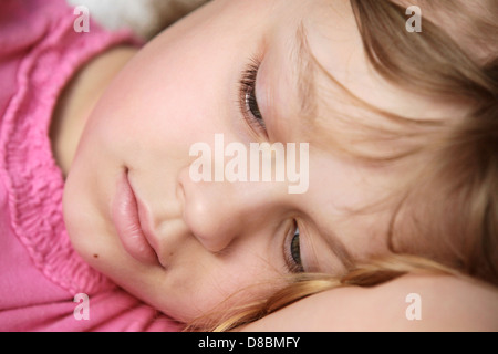 Closeup portrait de mentir petit blond Caucasian girl in pink Banque D'Images