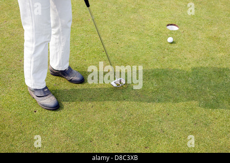 Les femmes en pantalon blanc tente de putt la balle sur le green de golf Banque D'Images