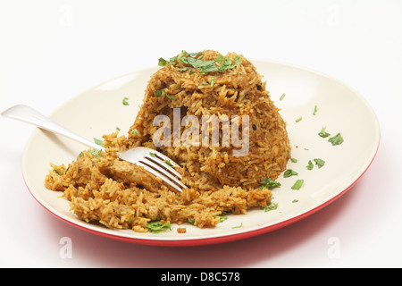 Une assiette de poulet biryani indien traditionnel, garni de coriandre (cilantro) et de feuilles de menthe sur une assiette avec une fourchette Banque D'Images